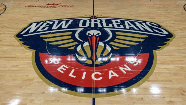 The New Orleans Pelicans logo sits at center court in the Smoothie King Center on a polished wooden basketball floor.