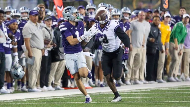 Jayce Brown and another LSU player leap for a pass as coaches and teammates look on from the sideline.