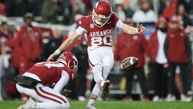 Scott Starzyk of Arkansas kicks a field goal with help from a teammate holding the ball during a game against LSU.