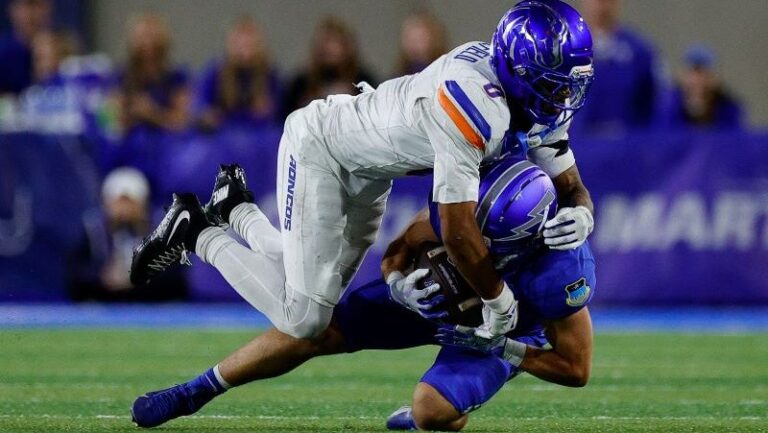 Ty Benefield of the Tigers tackles a Boise St player in blue as he runs with the ball on the field.
