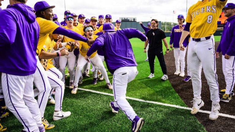 A baseball player runs toward cheering teammates in yellow and purple after LSU’s series win on the field.