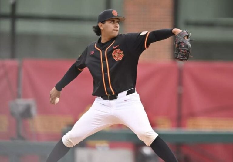 A baseball player in black and orange winds up to pitch, his stance reflecting the dramatic poise of a Velazquez portrait.