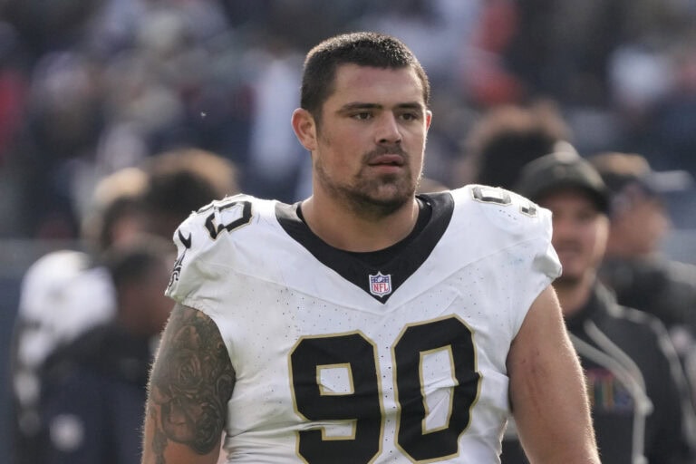 Bryan Bresee of the Saints, in a white and black jersey with number 90, stands on the field during a game facing forward.