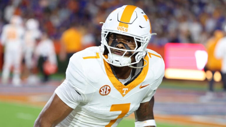A Tennessee Volunteers football player in a white and orange uniform stands on the field amid rumors about Arion Carter.