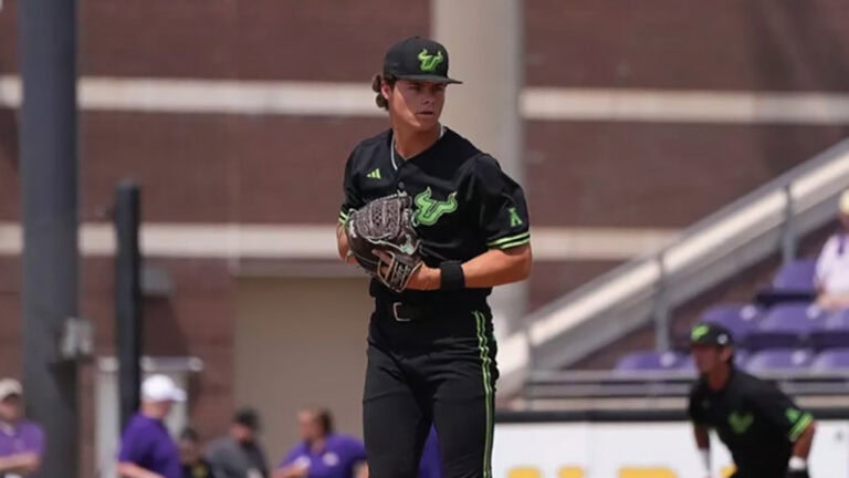 Kaden Smith, wearing a black uniform with green trim, stands on the pitcher’s mound ready to throw.