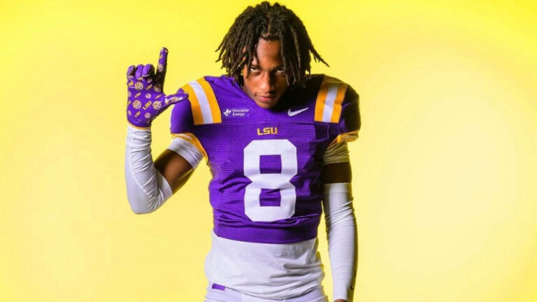 Jayden Anding of LSU’s 2027 class raises his left hand in an "L" shape against a yellow background.