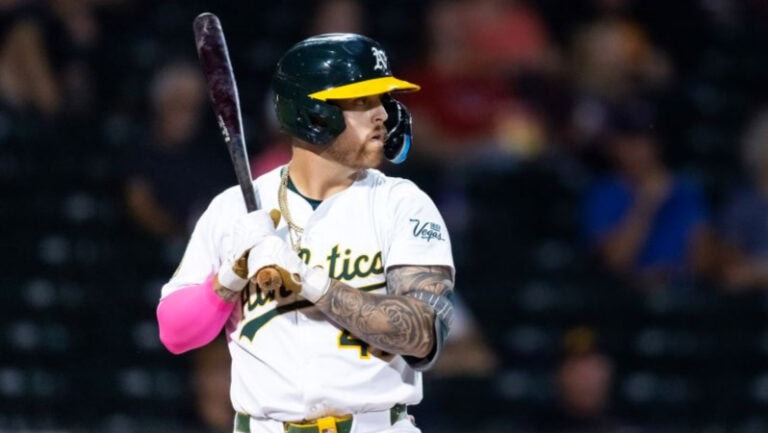 Tommy Whit, wearing his Oakland Athletics uniform and helmet, stands ready at bat as blurred fans fill the background.