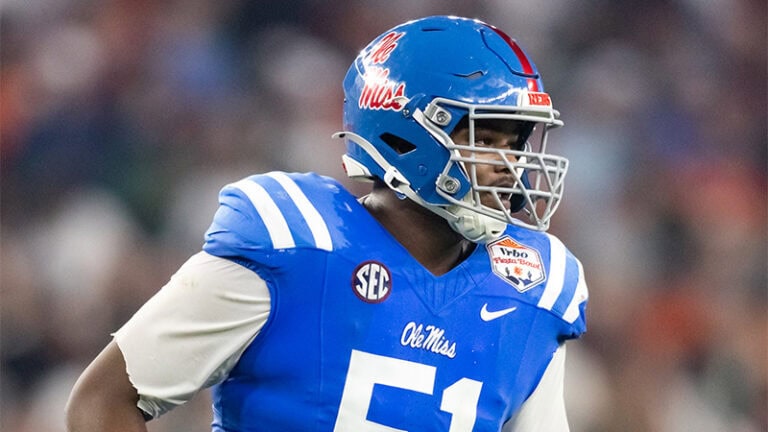 Number 51, wearing a blue Ole Miss football uniform and helmet, stands on the field during a game, facing right.