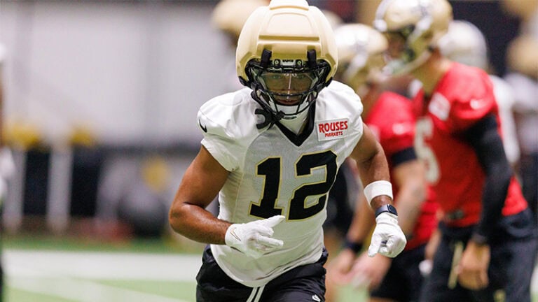 Chris Olave runs during training camp, with teammates close by on the ninth day.