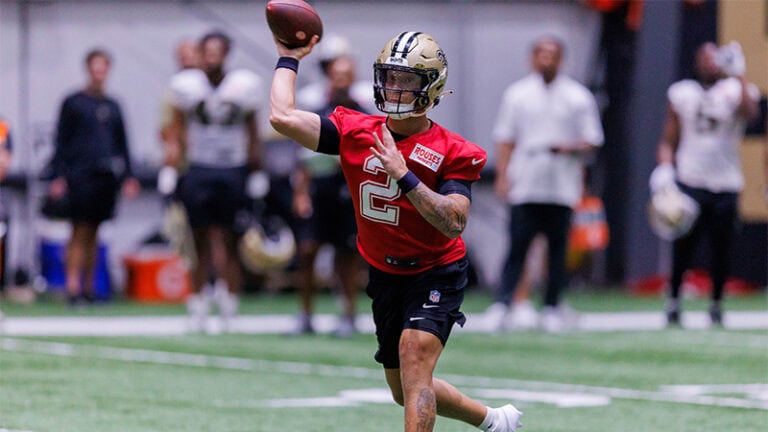 Spencer Rattler gets ready to throw at camp while teammates watch in the background.