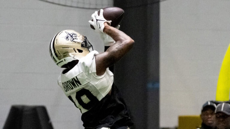 A Saints player catches a pass during an indoor training camp practice.