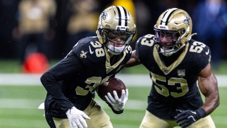 Two Saints players in black uniforms excel in the preseason opener, with number 38 carrying the ball and 53 running beside him.