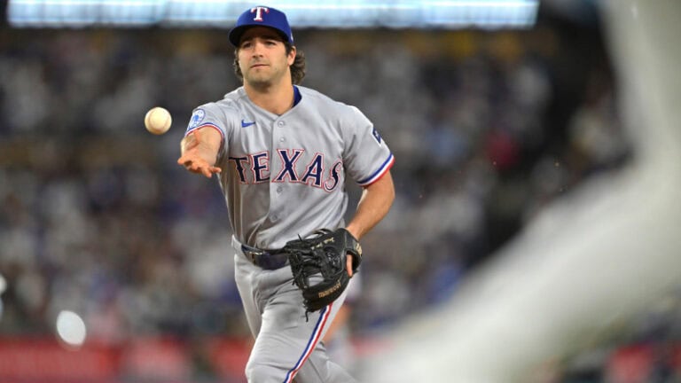 Josh Smith of the Texas Rangers, in a gray uniform, throws a baseball during a game amid trade deadline speculation.