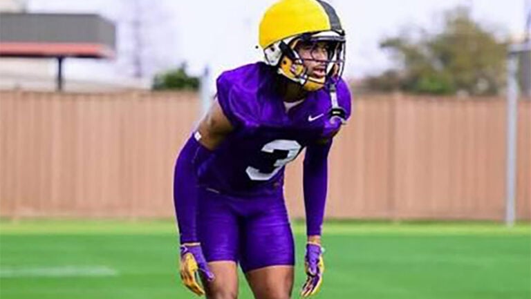 DJ Pickett stands slightly bent forward on a grassy field, looking ahead among teammates.