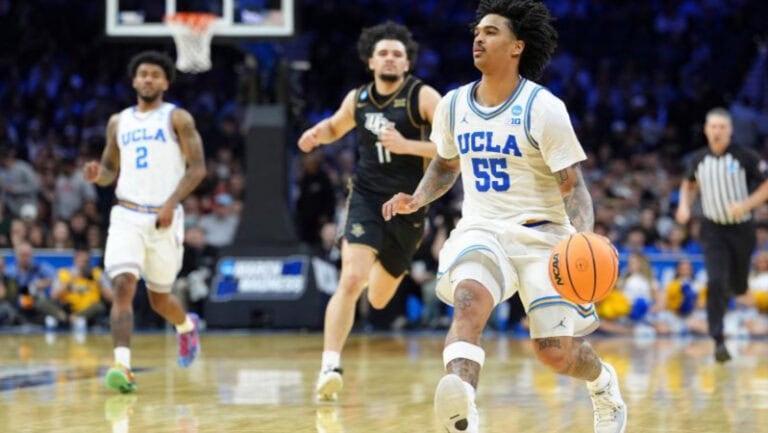 Skyy Clark of UCLA dribbles upcourt during a game, with teammates and LSU players trailing behind him.