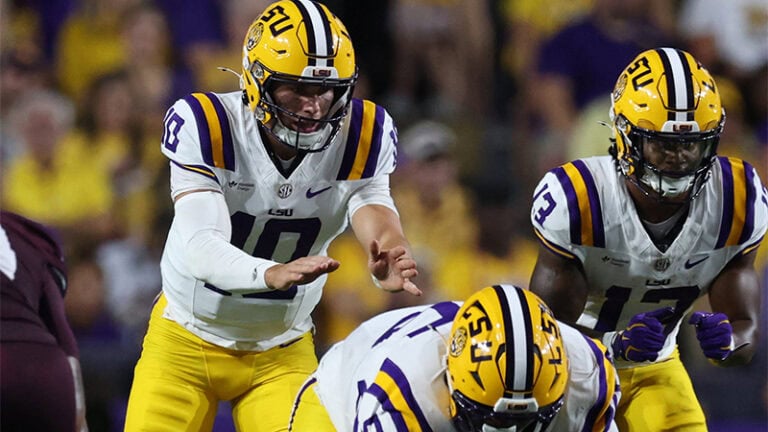 LSU football players in yellow helmets and white uniforms line up, focused and determined before the next play.