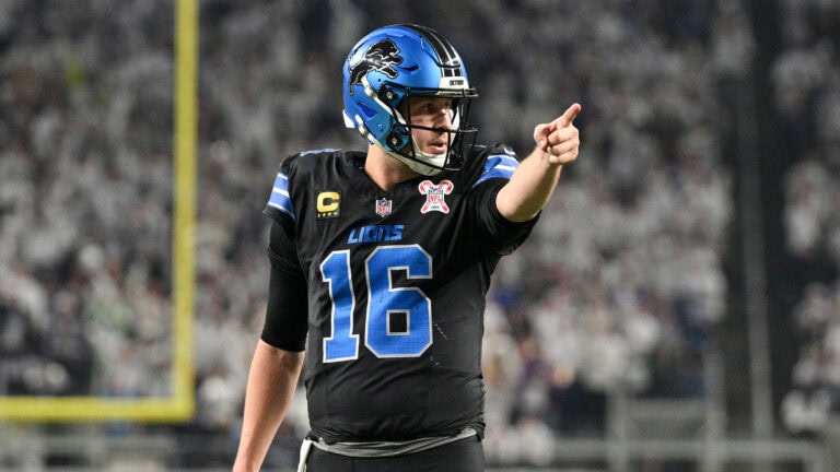 Detroit Lions player in a black uniform points, signaling an offensive play during game prep against the Saints.