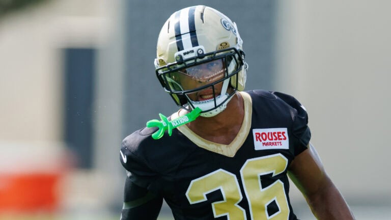 Lorenzo Styles Jr., wearing black and gold #36, stands in a helmet with visor and a green mouthguard attached to his face mask.