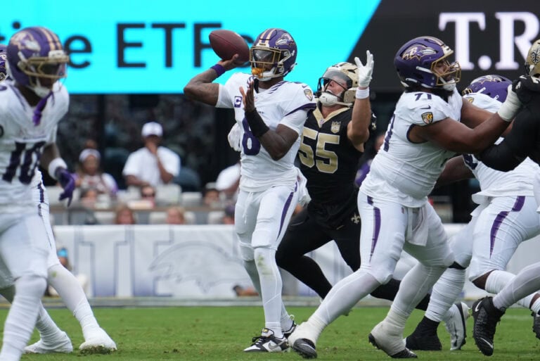 A football player in a purple uniform readies to throw, surrounded by teammates and defenders, evoking a New Orleans Saints play.