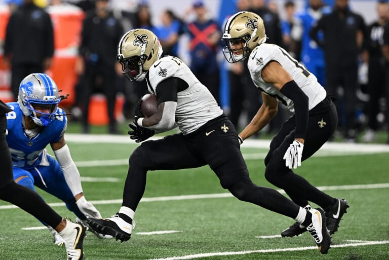 A Saints player runs with the football as Detroit Lions defenders close in during an exciting game.