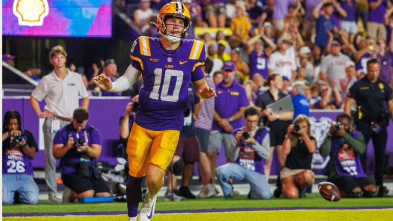 LSU football player #10 sprints with the ball, focused ahead as the crowd cheers, energized by hopes for the 2027 playoff title.
