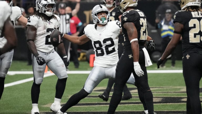 A player in a white uniform celebrates with the ball as an opponent in black looks on during a football game.