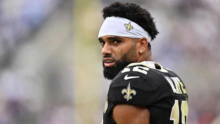 New Orleans Saints receiver Chris Olave looks over his shoulder while wearing a team jersey and white headband vs the Giants.