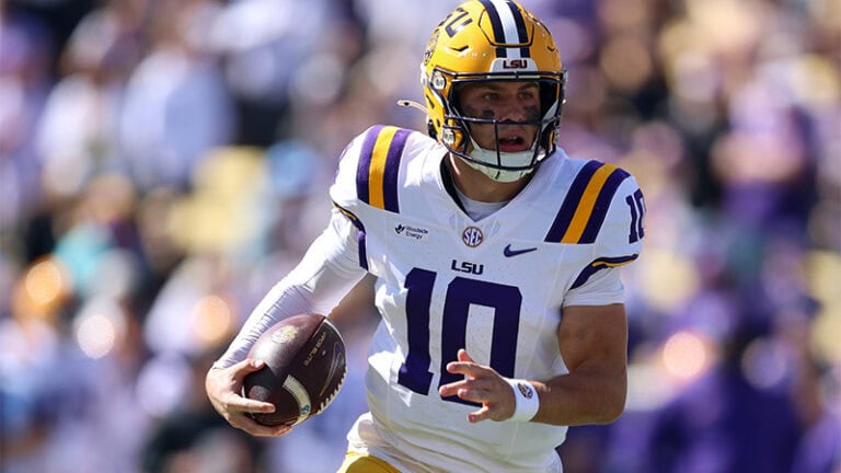 An LSU player in a white uniform runs with the football during a game against Mississippi State.