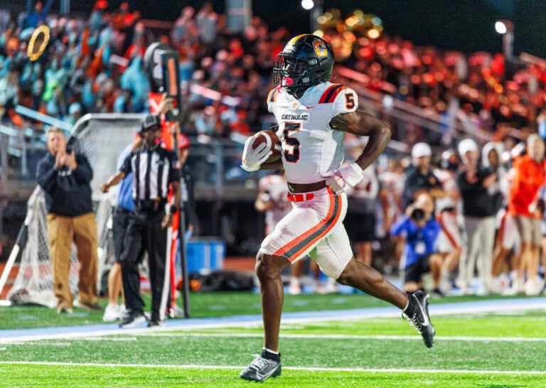 A Louisiana high school football player in a white number 5 jersey runs across the field during a game.