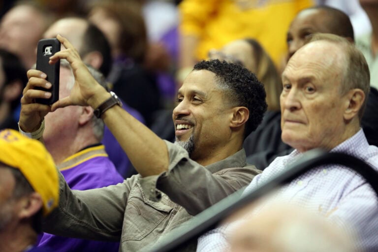 Dale Brown smiles as he takes a selfie in a crowded stadium.