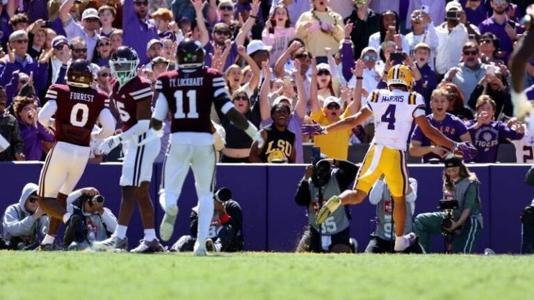 LSU football players celebrate on the field before a cheering crowd.