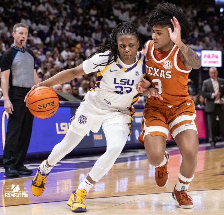 An LSU women’s basketball player dribbles the ball while being defended by a Texas player on the court.