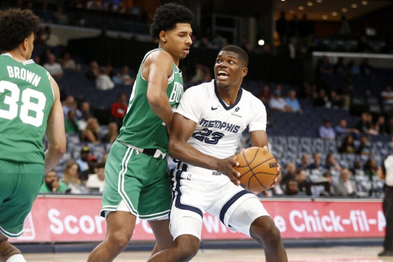 RJ Luis in a white Memphis Grizzlies uniform holds the ball while being defended by a player in a green jersey.