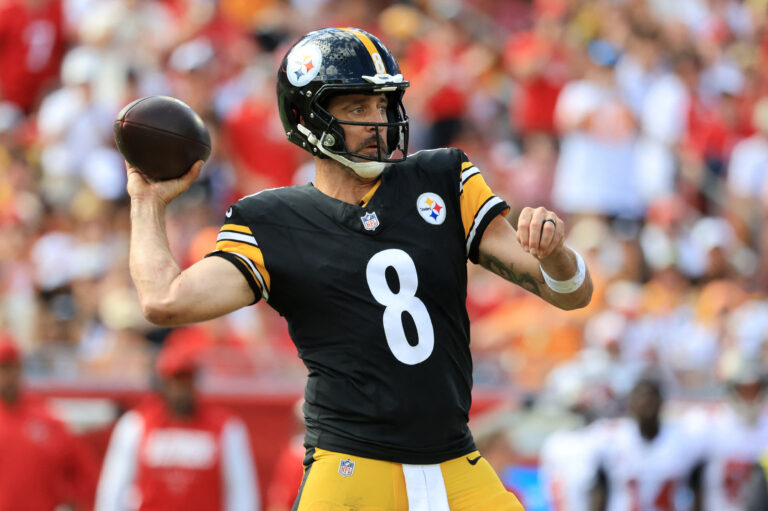 A Pittsburgh Steelers quarterback in a black jersey throws a football during an NFL game against the Saints.