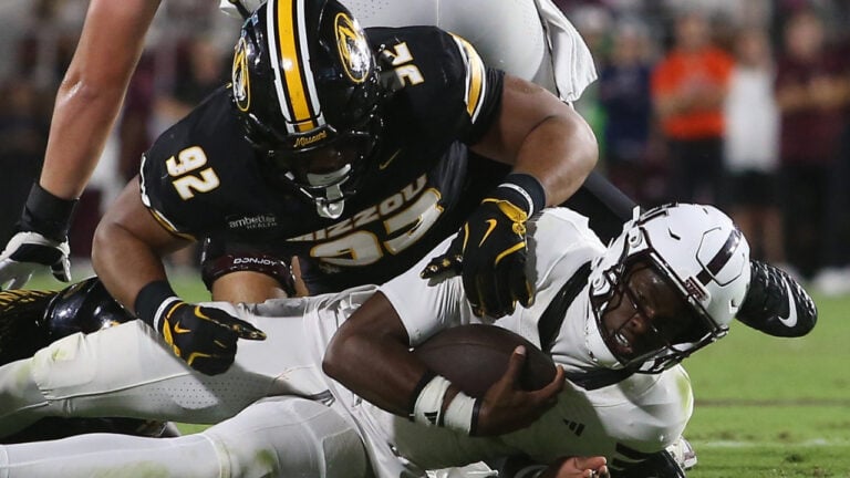 A Missouri player in a black uniform tackles an opponent in white to the ground during a Week 7 college football game.