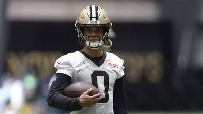 New Orleans Saints wide receiver Jordyn Tyson wears a white practice jersey and holds a football.